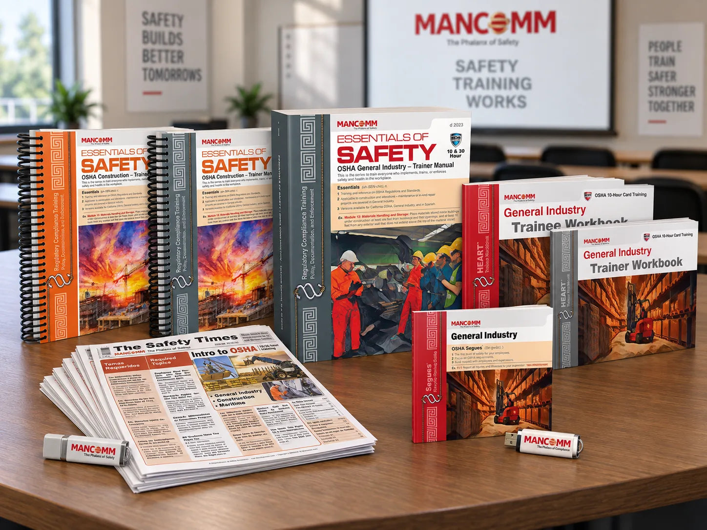 Mancomm training kit: Essentials of Safety trainer manuals, HEART trainer and trainee workbooks, Safety Times newspapers and USB slide decks on a classroom table